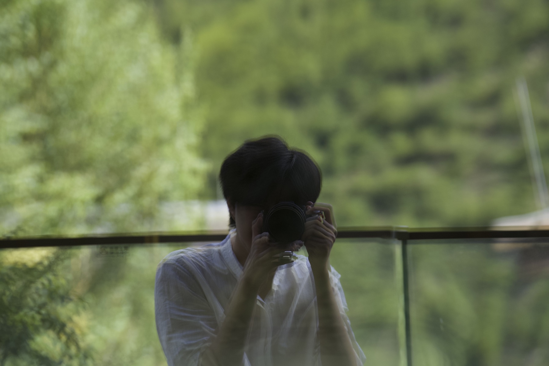 Ke holding his camera amid green reflections